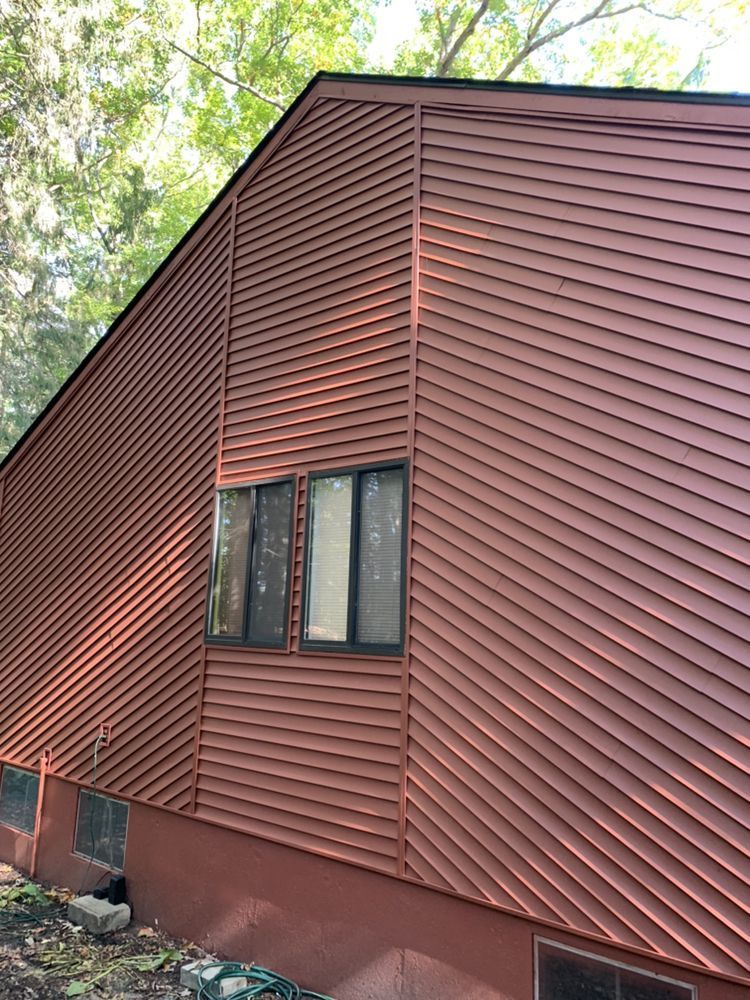 Red-brown siding on a house with dark framed windows.