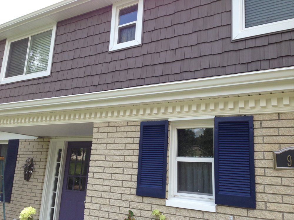 Two-story house with brick exterior, brown shingle siding, white trim, and blue shutters.