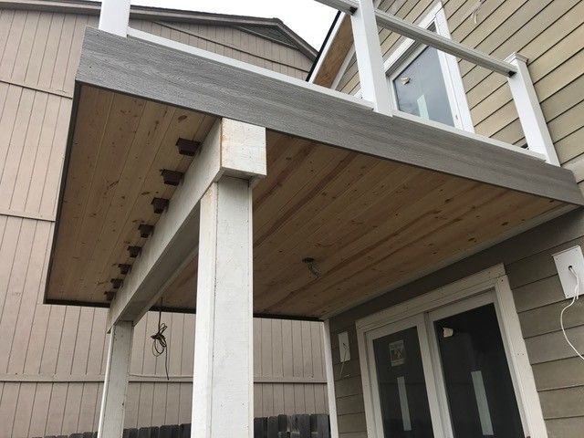 Wooden deck with gray composite boards, white posts, and railing. Underside is natural wood.