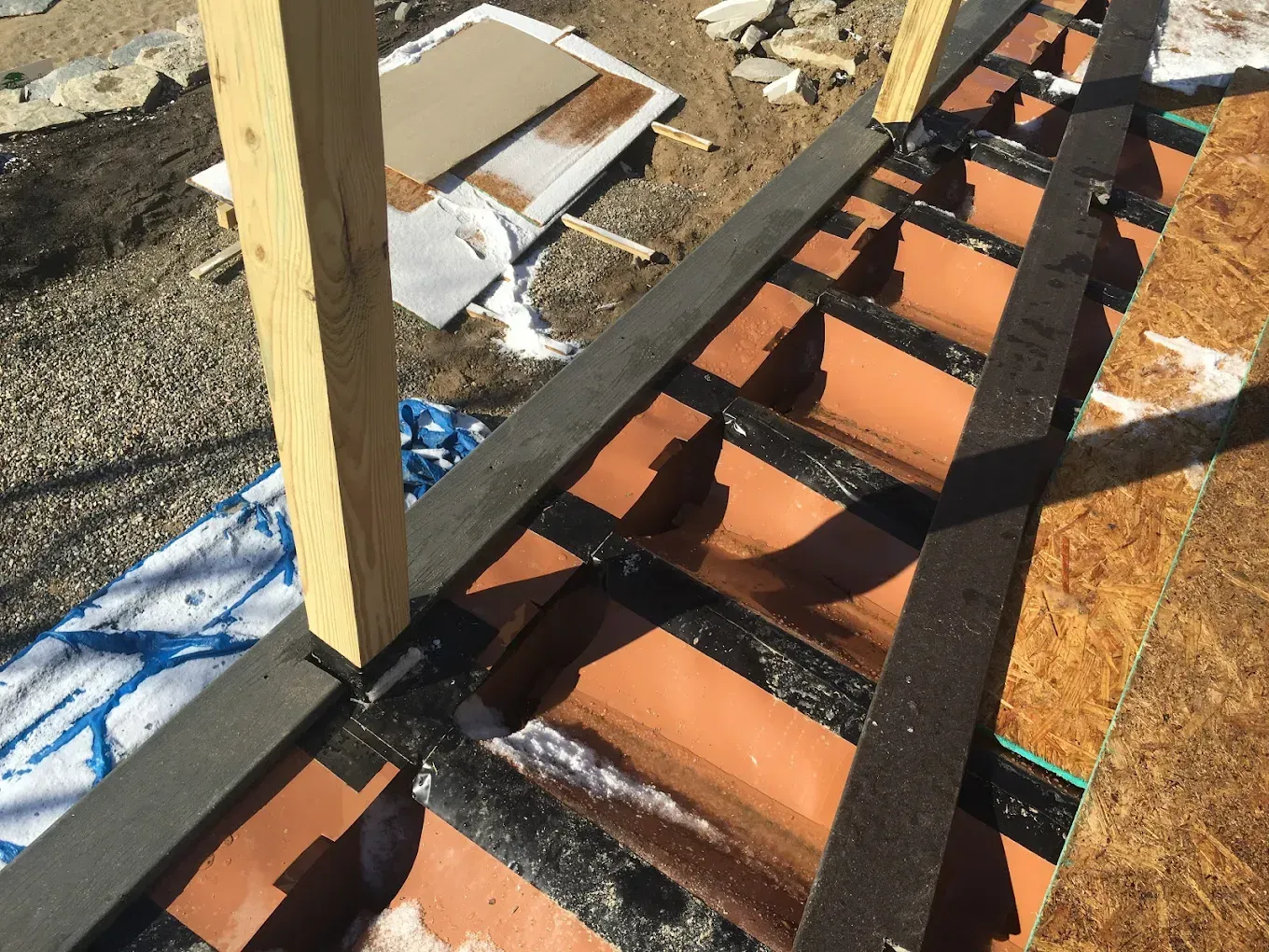 Construction of a tiled roof with dark flashing and a wooden support beam.