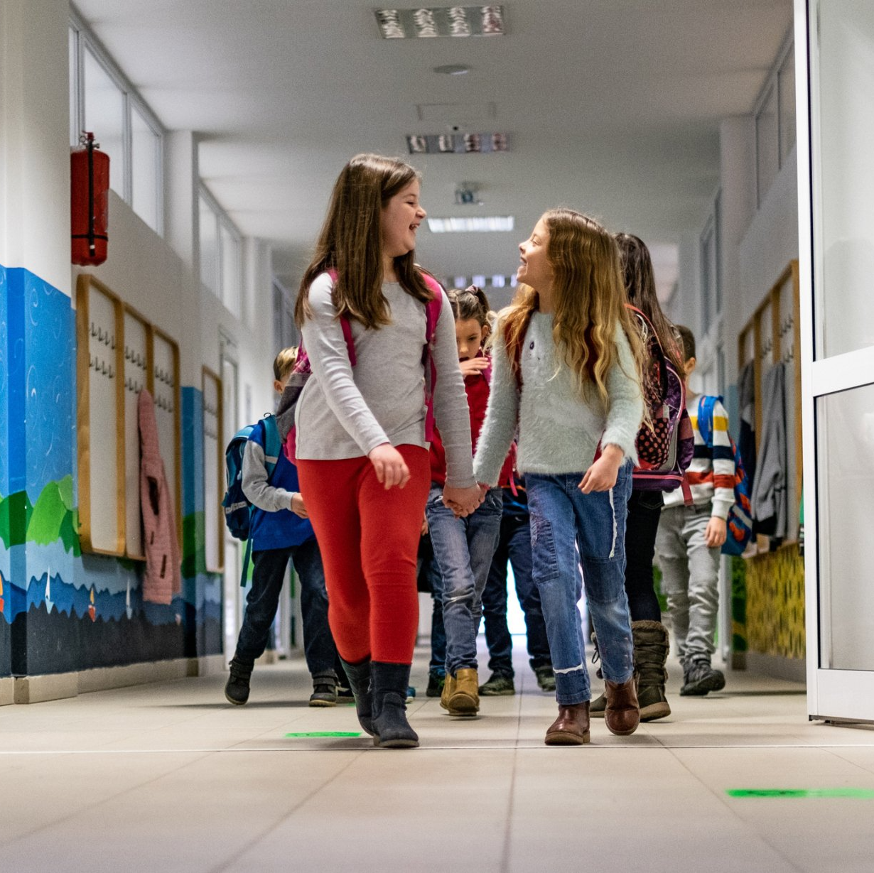 Portrait of smiling girls walking through high school corridor after their class