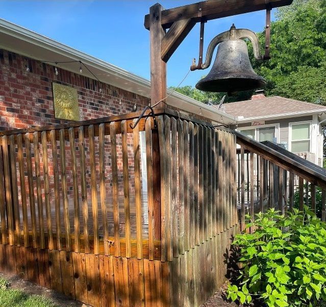 A wooden fence with a bell hanging from it