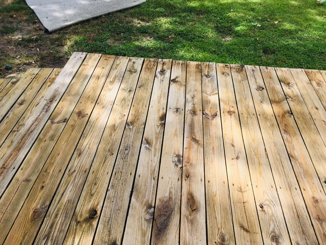 A wooden deck is sitting on top of a lush green field.