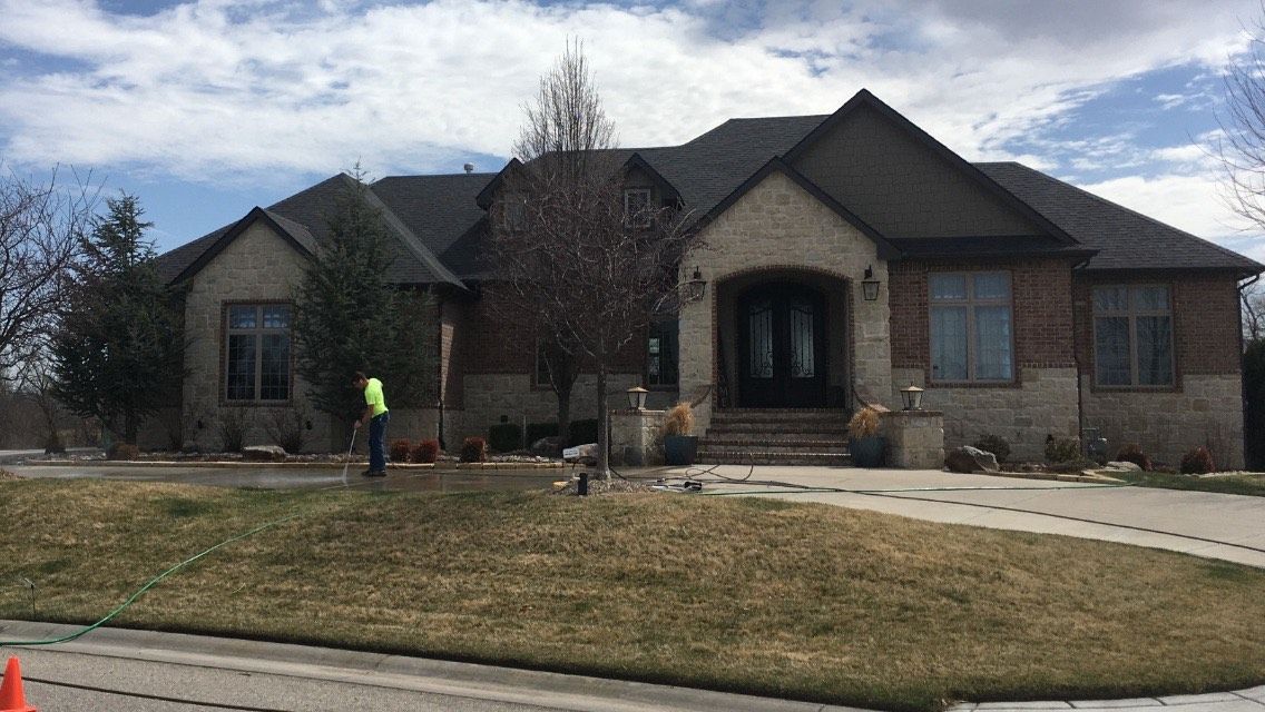 A man in a yellow vest is standing in front of a large brick house.