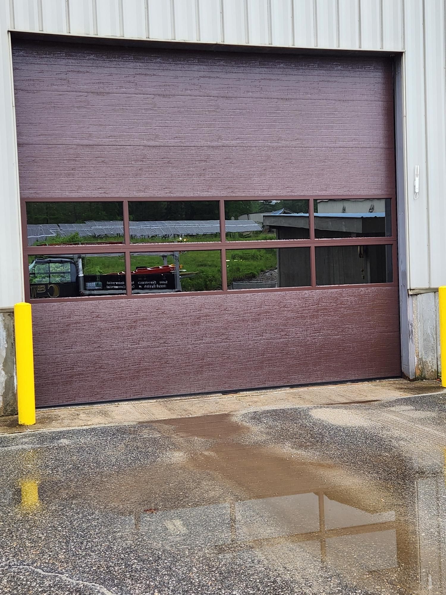 A brown garage door with a lot of windows is sitting in front of a building.
