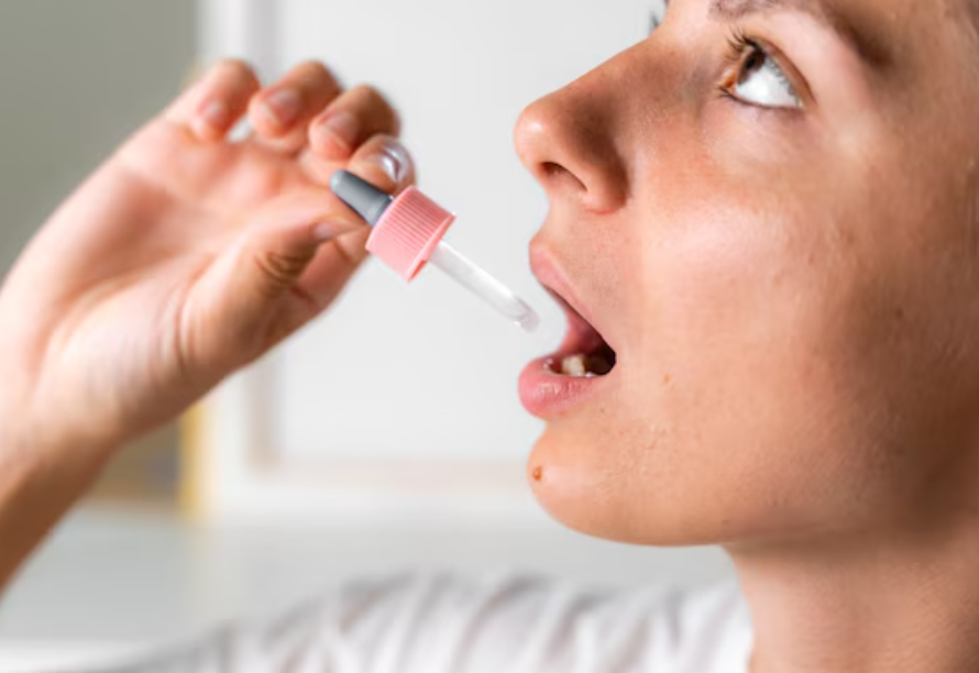 Mulher adulta aplicando vacina para alergia sublingual, pingando as gotas abaixo da língua.