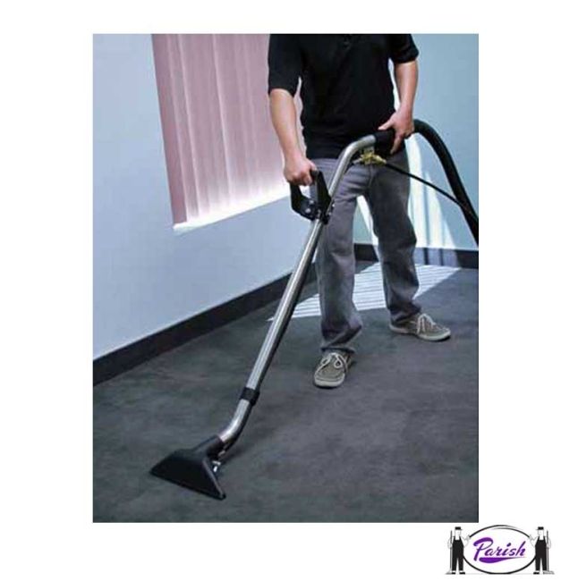 Woman vacuuming a carpeted living room with a teal and gray vacuum cleaner.