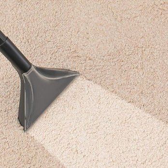 Vacuum cleaner head cleaning a beige carpet, creating a clean stripe.