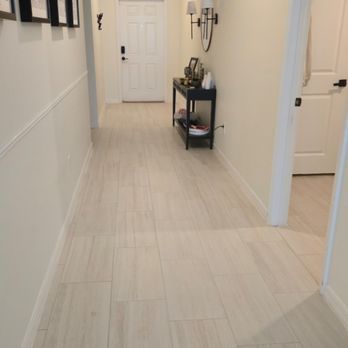 Hallway with beige tile floor, off-white walls, and a black table with decor.