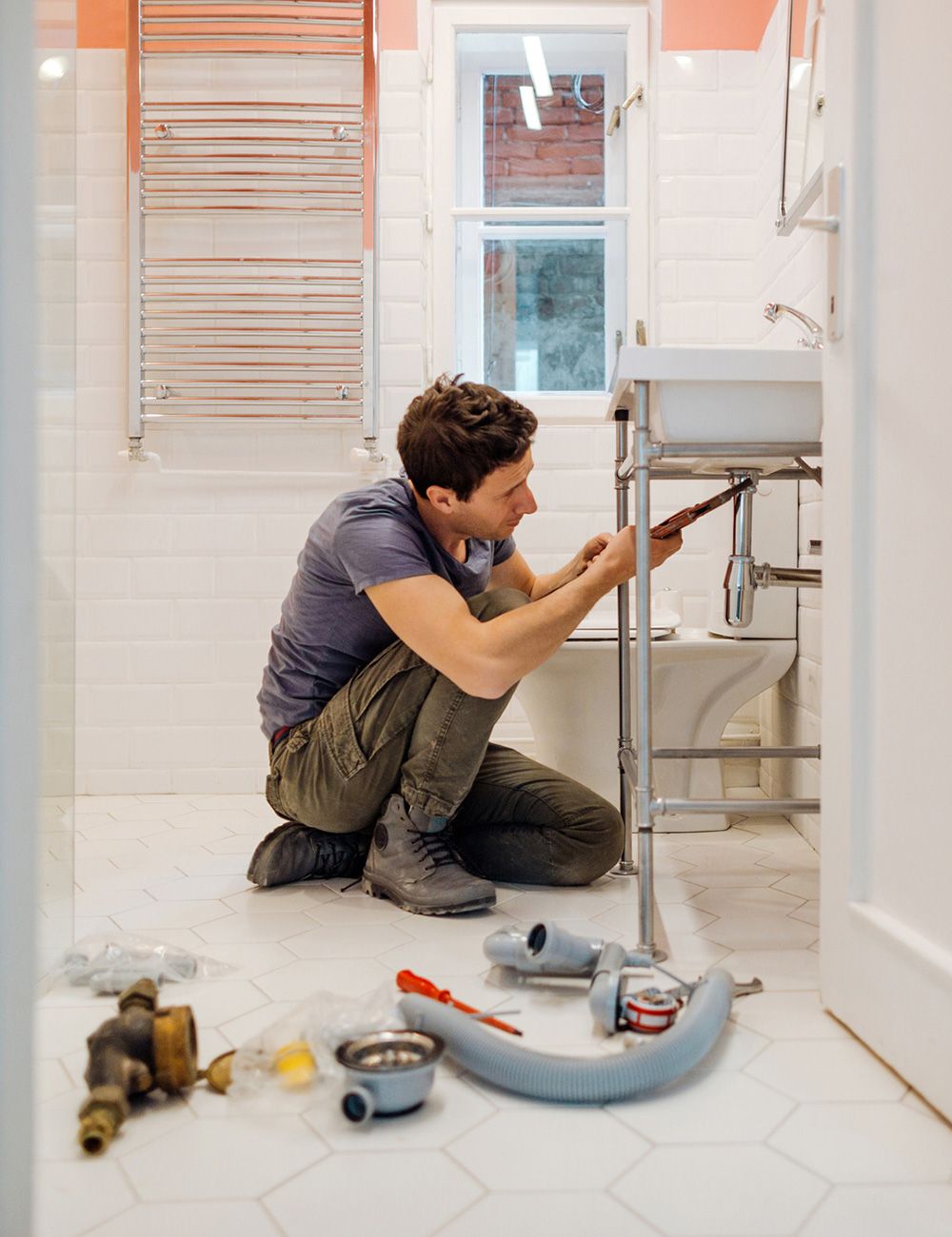 Man Fixing a Leak Under the Bathroom Sink — St. Louis, MO — Shamrock Sewer & Drain