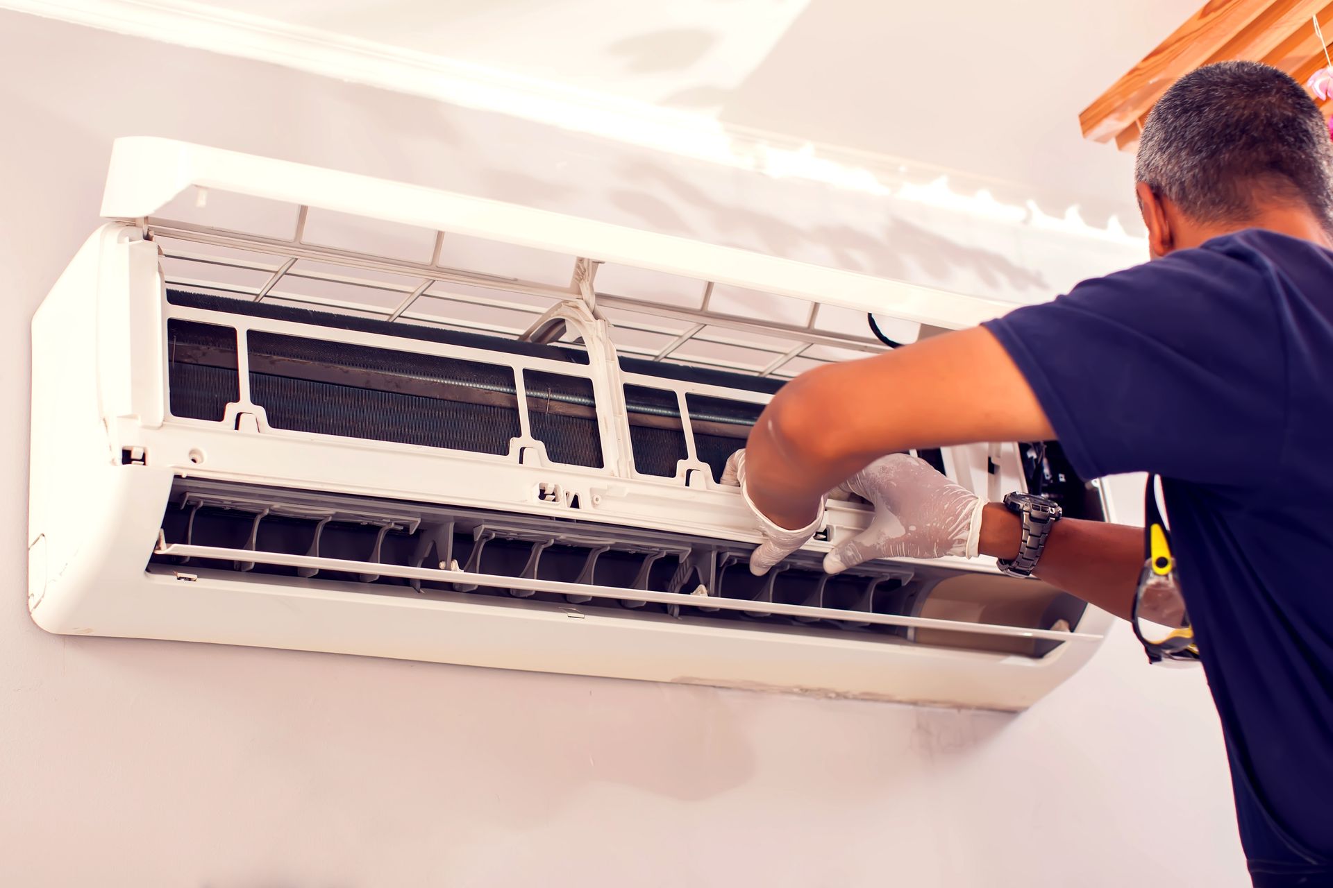 A technician fixing an air conditioning on the wall.
