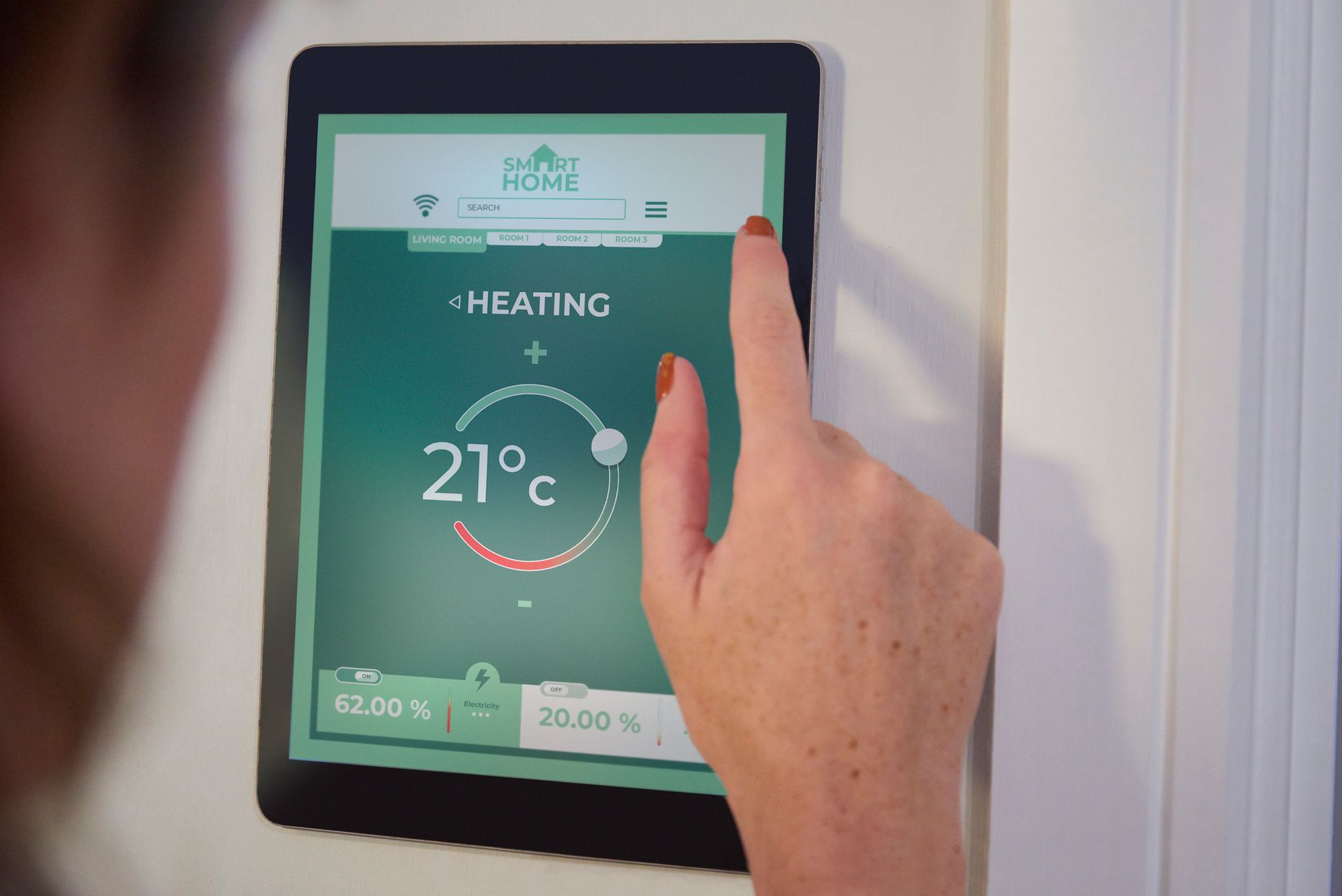 Person adjusting smart home heating on a tablet displaying 21°C.