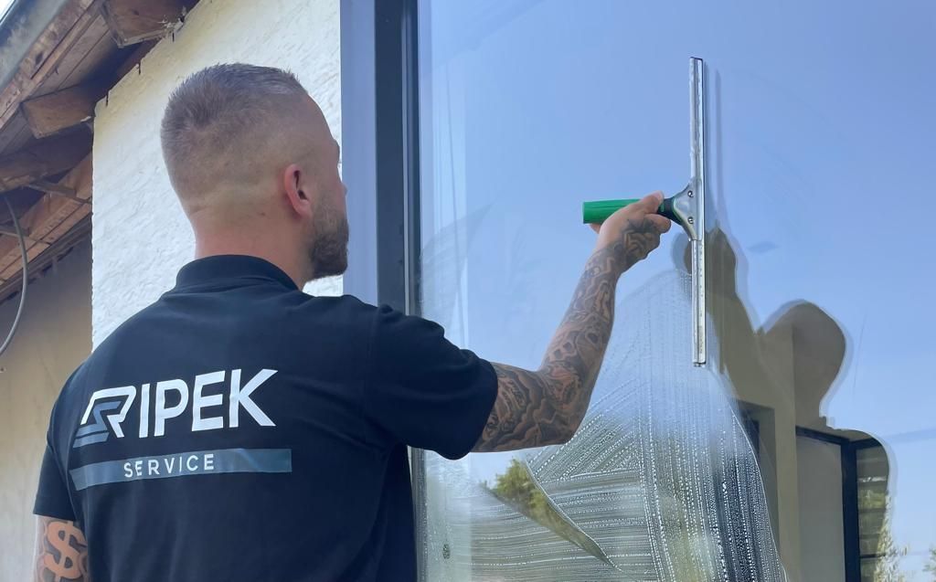 Een man maakt een raam schoon met een trekker.