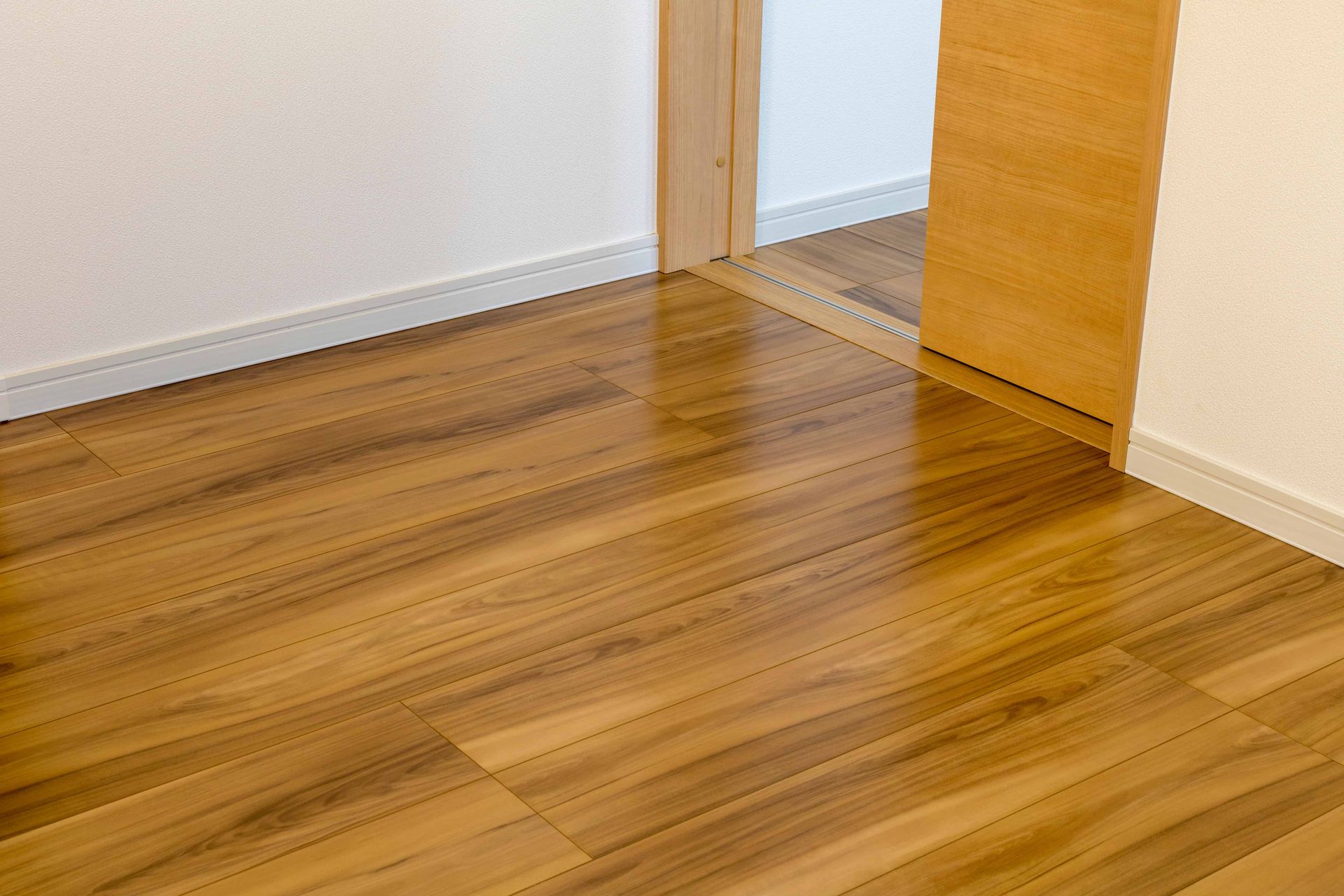A wooden floor in a room next to a door.