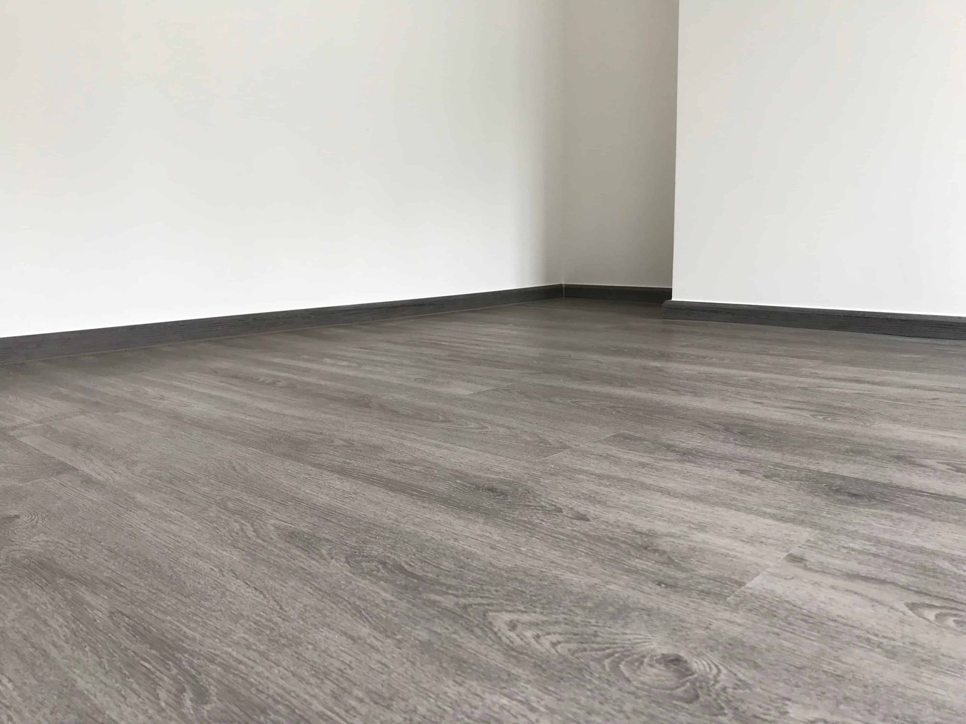 An empty room with a wooden floor and white walls.