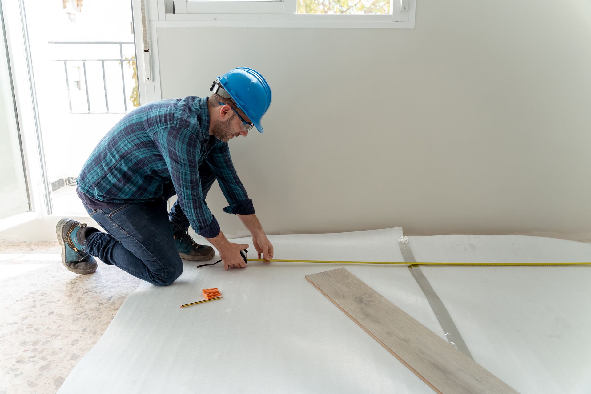 A man is measuring a wooden floor with a tape measure.