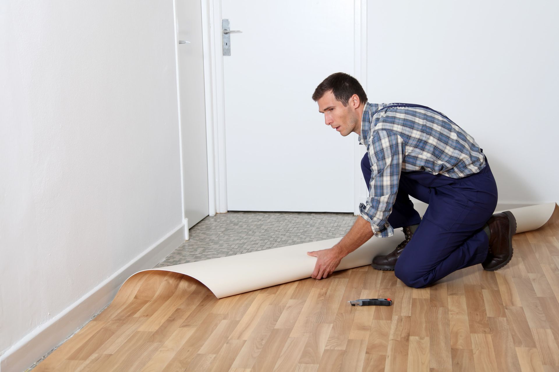 A man is kneeling down to install a hardwood floor.
