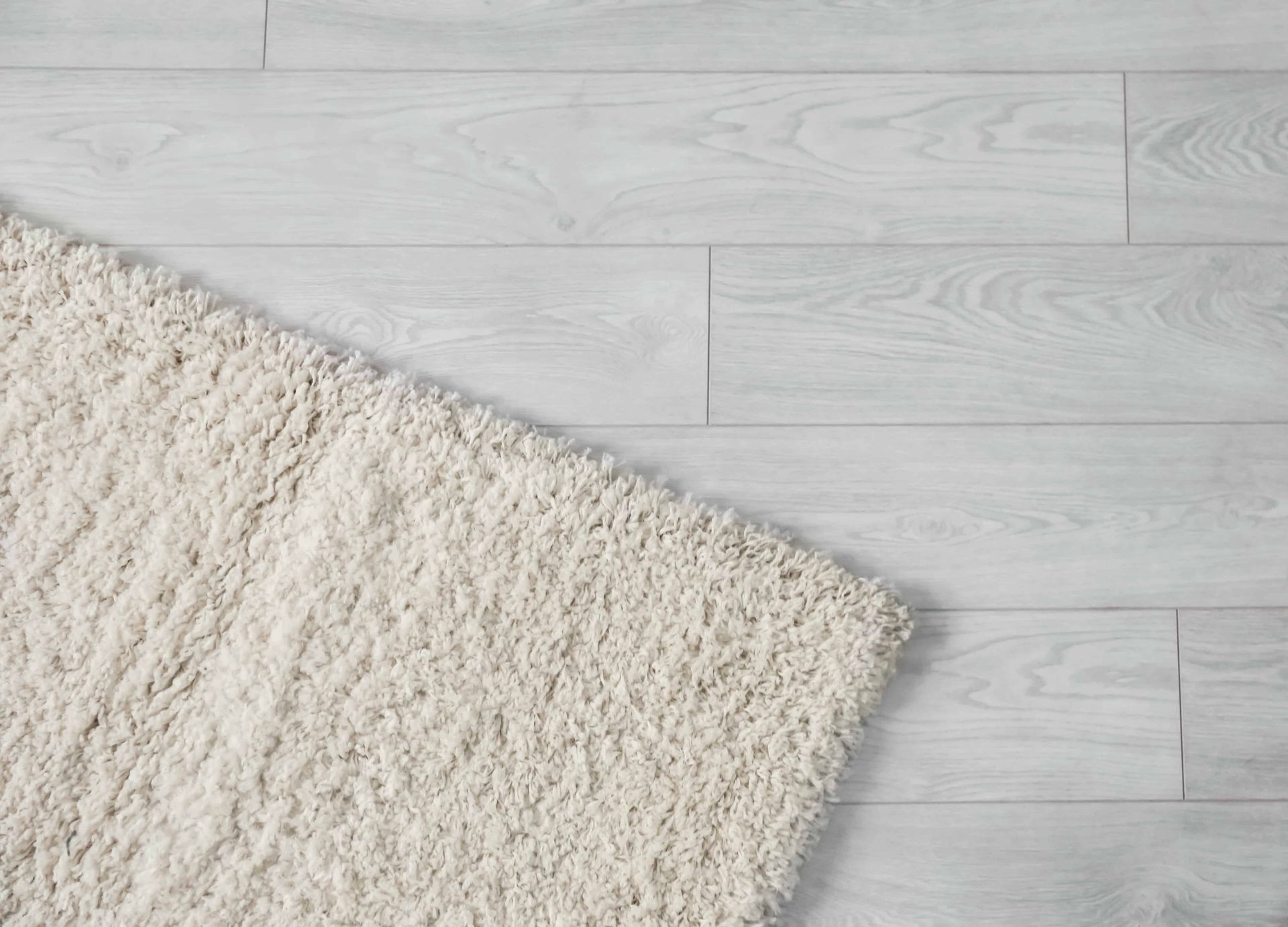 A white rug is laying on a white wooden floor.