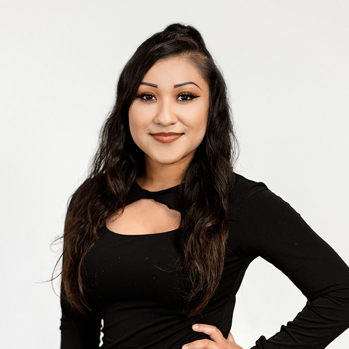 A woman in a black top is standing with her hand on her hip