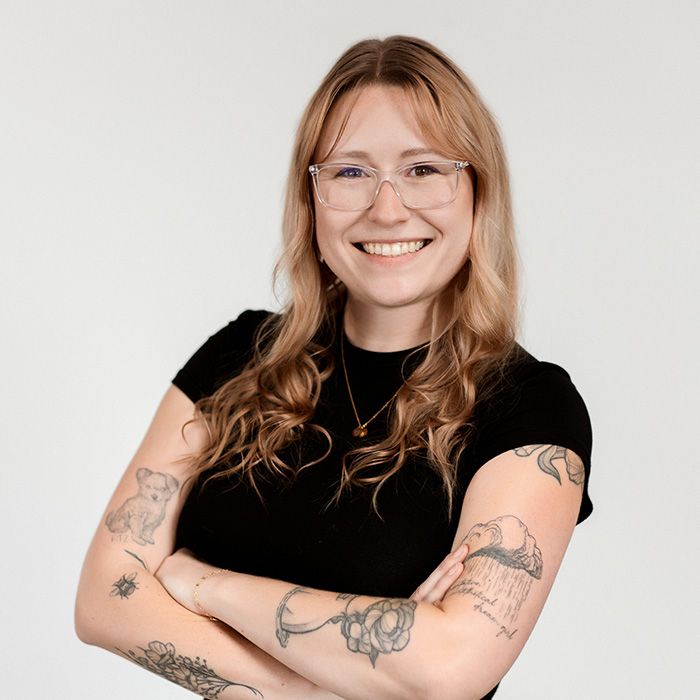 A woman with tattoos on her arms wearing glasses and a black shirt