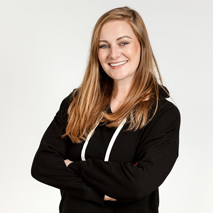 A smiling woman wearing a black sweatshirt with her arms crossed