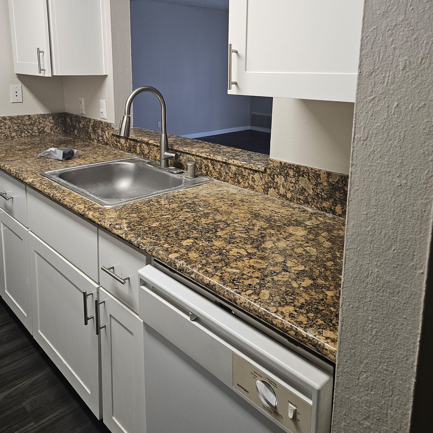 Kitchen with white cabinets, granite countertops, stainless sink, and dishwasher.