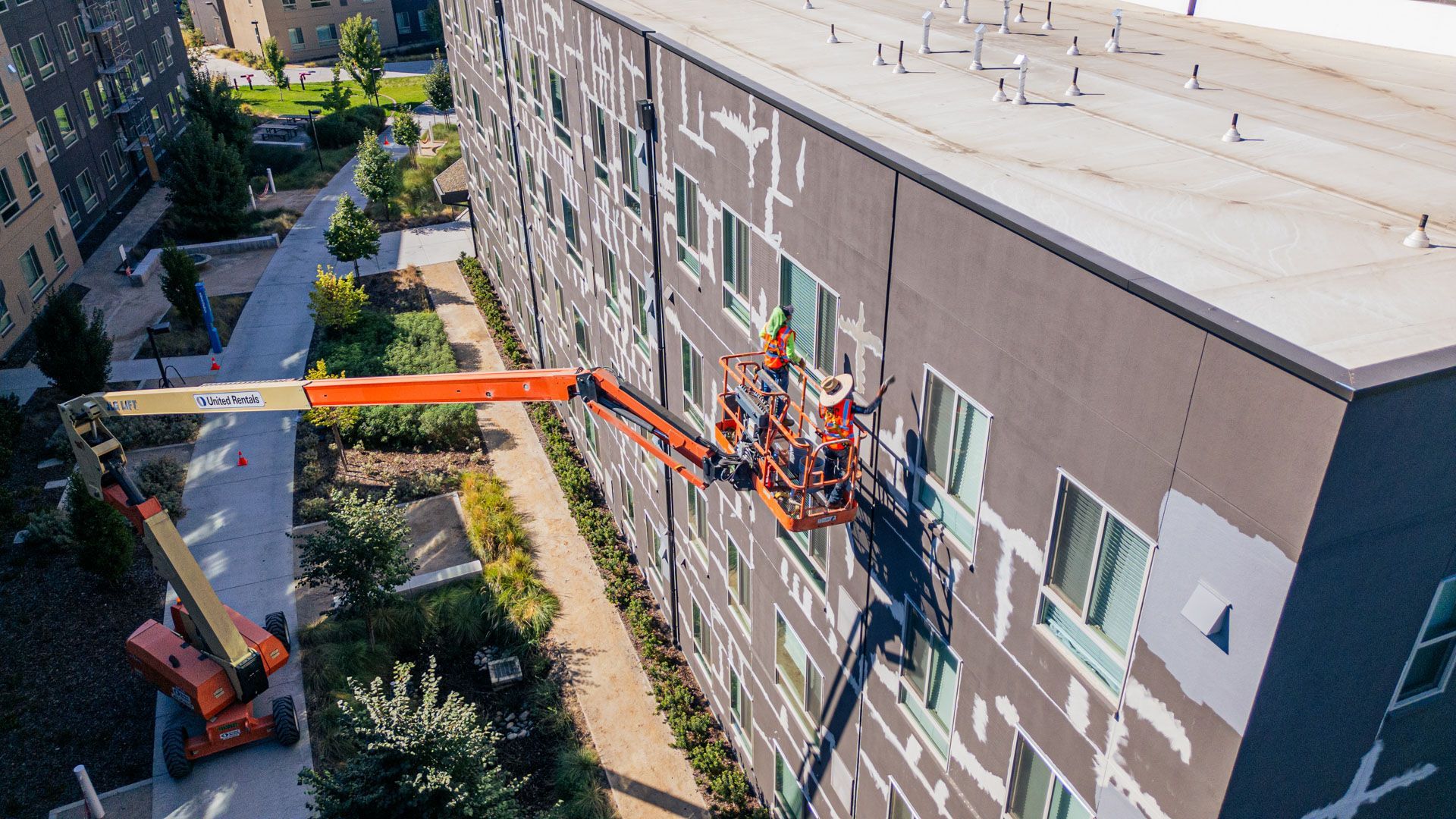 Cherry picker lifts workers to a building facade for exterior maintenance.