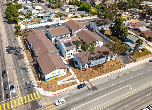 Aerial view of a large tan-roofed building at a busy street intersection in a suburban neighborhood