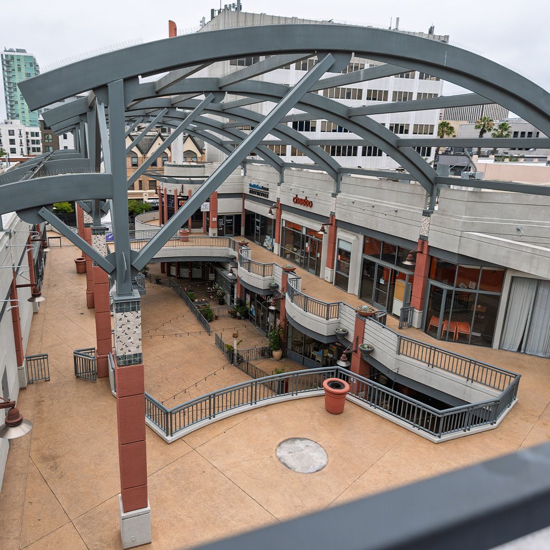 Elevated view of a mostly empty outdoor shopping center with gray metal archway roofing.