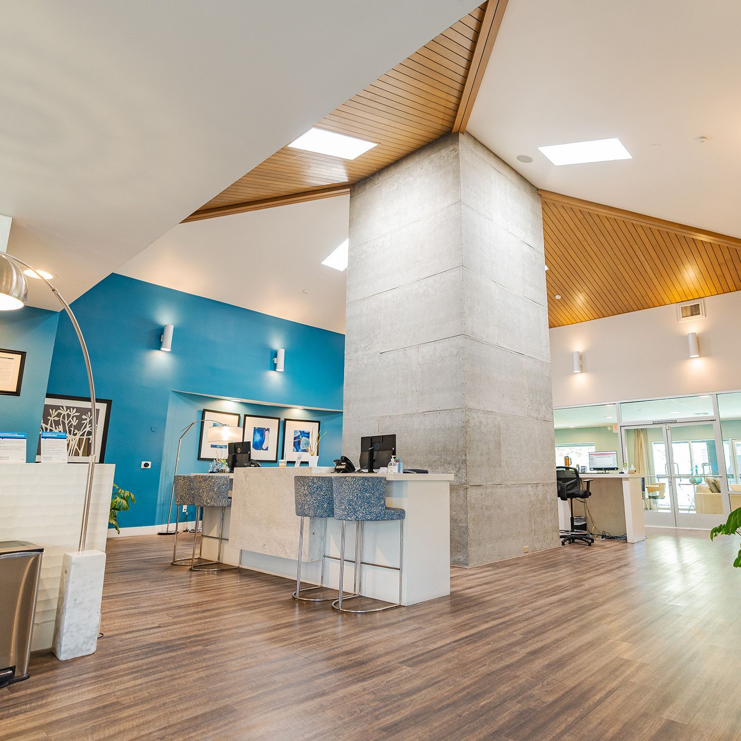 Modern lobby with reception desk, blue wall, wood ceiling, and pillar.