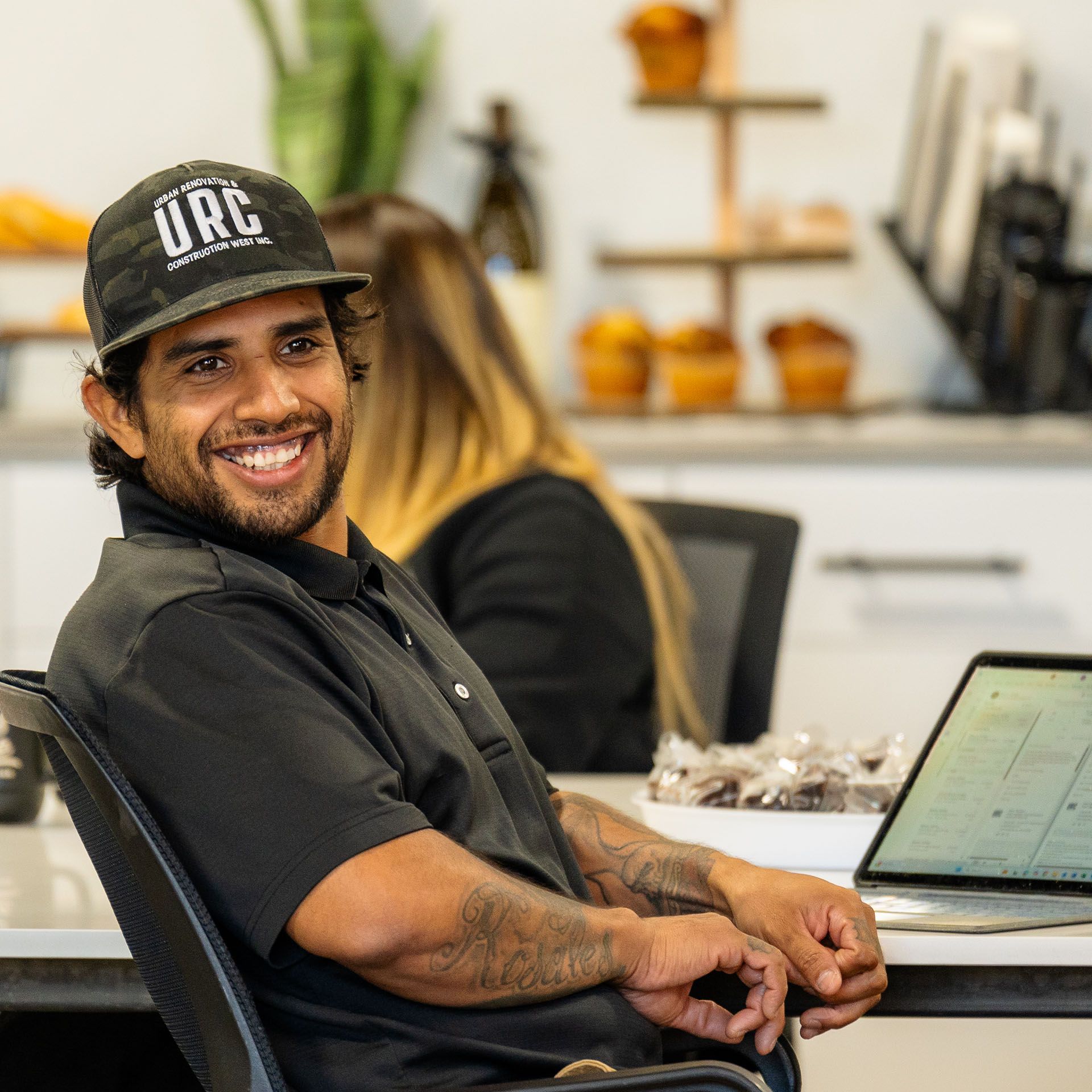 A man in a black shirt is smiling in a kitchen.