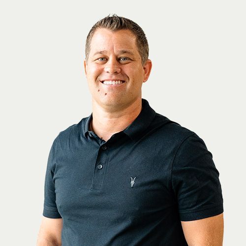 Man in black polo shirt smiling, torso up, against a white background.