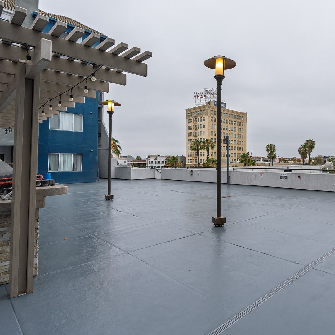 Rooftop view with light posts, a blue building, and a distant beige building on a cloudy day.