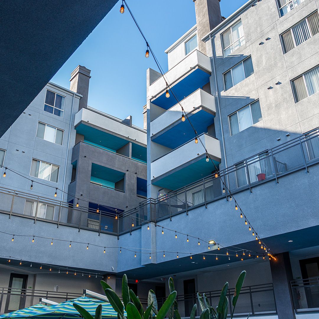 Apartment building with teal balconies, string lights, and a clear blue sky.