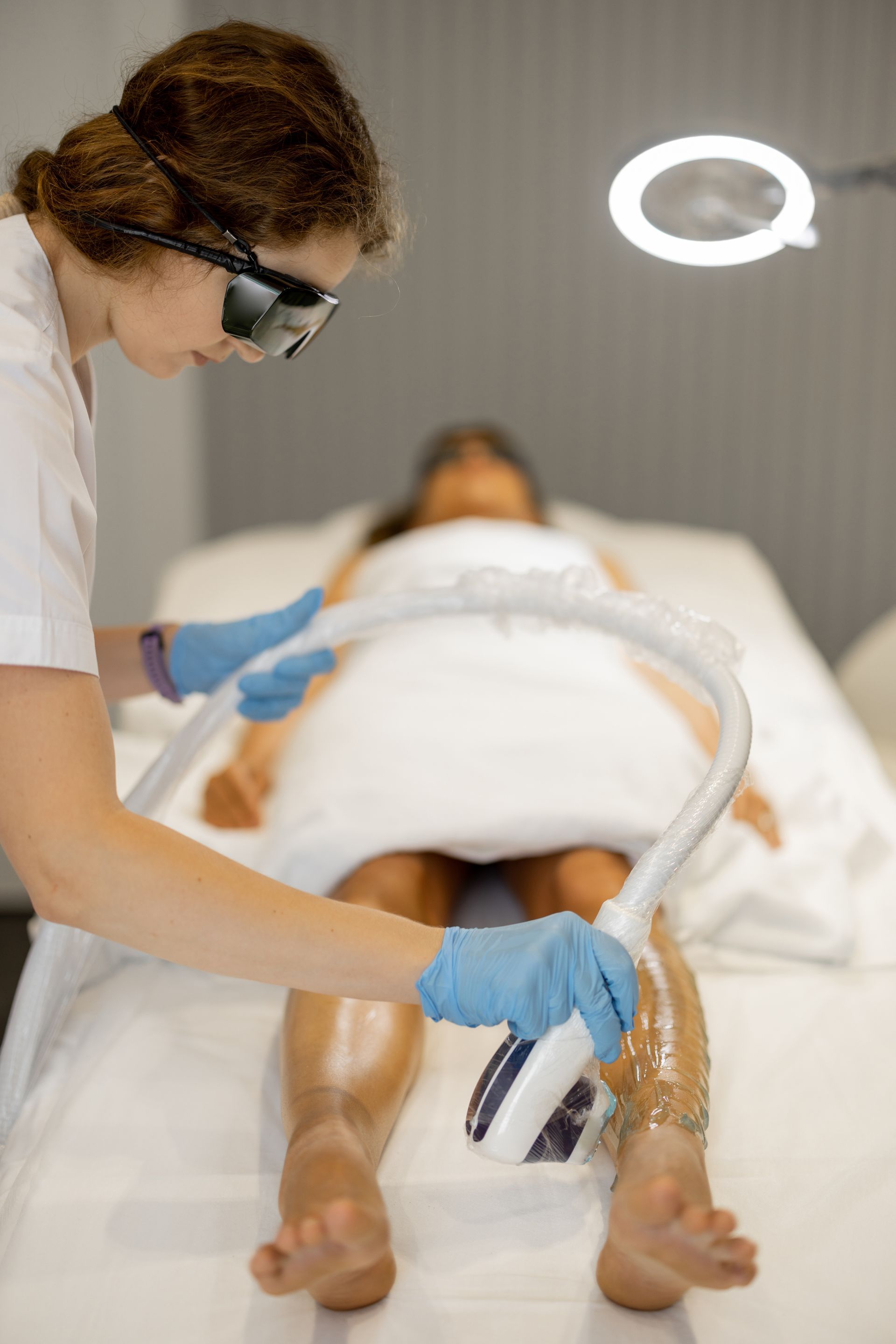 A woman is getting a laser hair removal treatment on her legs.