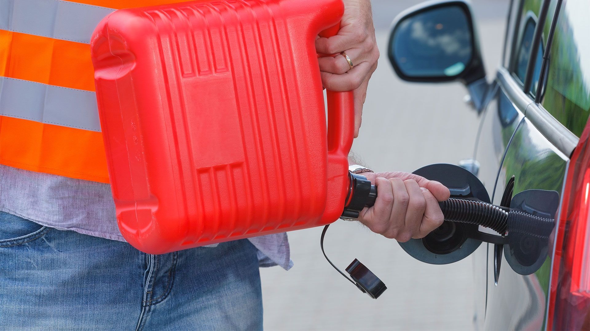 A person is pouring gas into a car at a gas station.