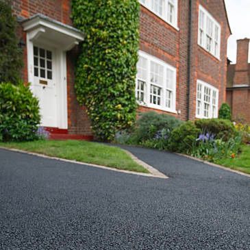 a brick house with a black driveway in front of it .