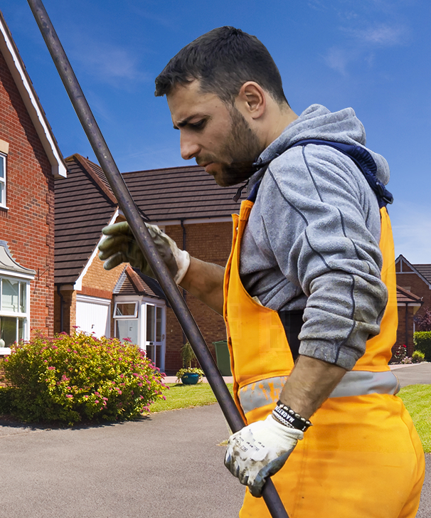 a man in orange overalls is holding a pole in front of a house
