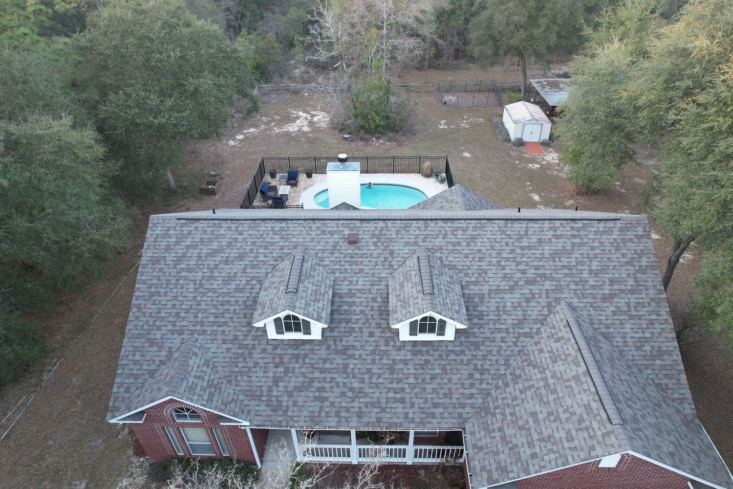 Aerial view of a house with a pool in the backyard surrounded by trees.
