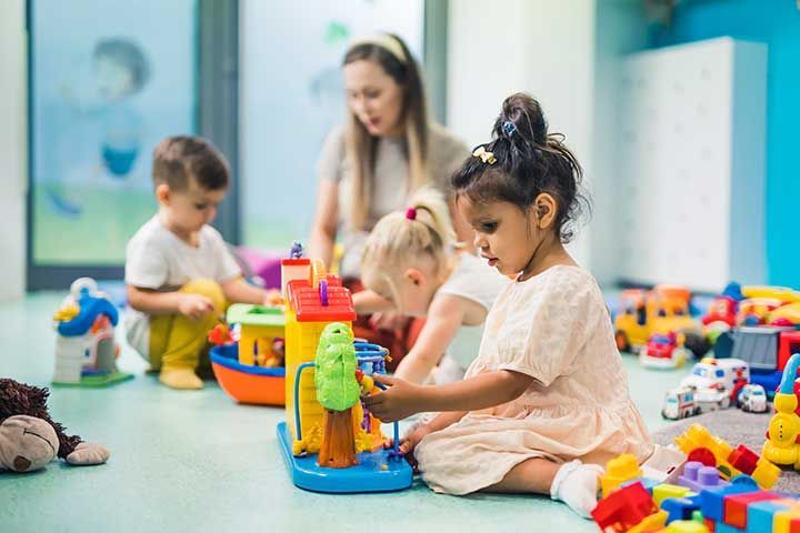 preschoolers building with toys and cubes and enjoying in kindergarten with teacher,