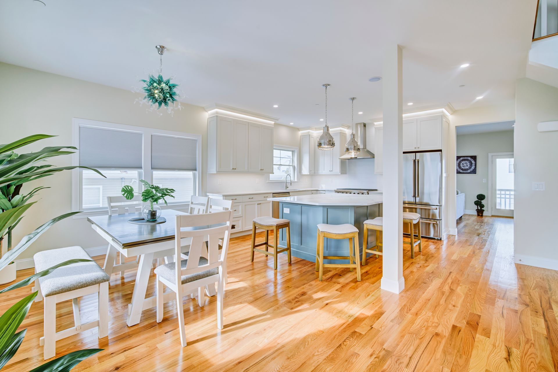 Spacious kitchen with island, dining table, hardwood floors, and natural light.