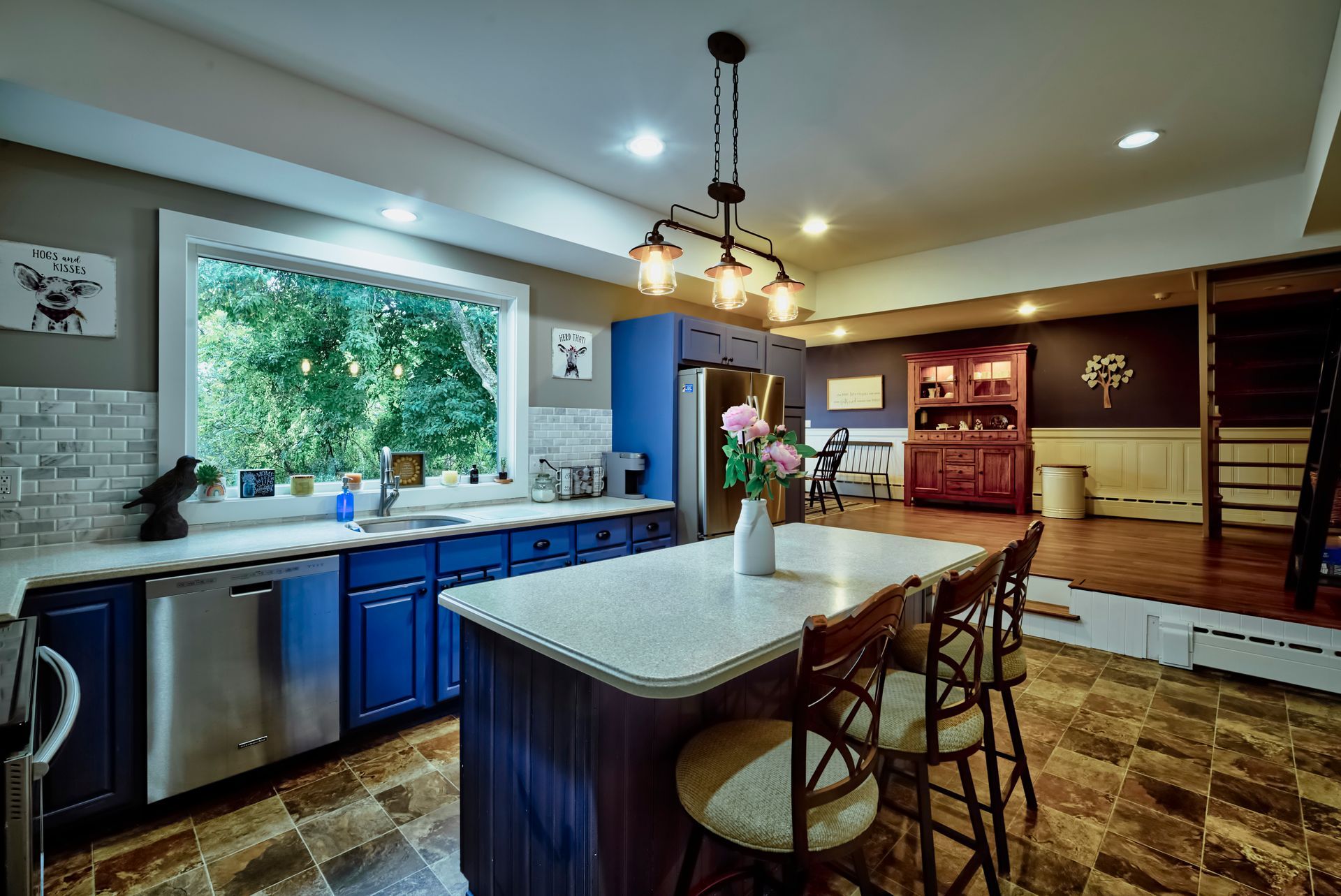 A kitchen with blue cabinets , white counter tops , stainless steel appliances , and a large island.
