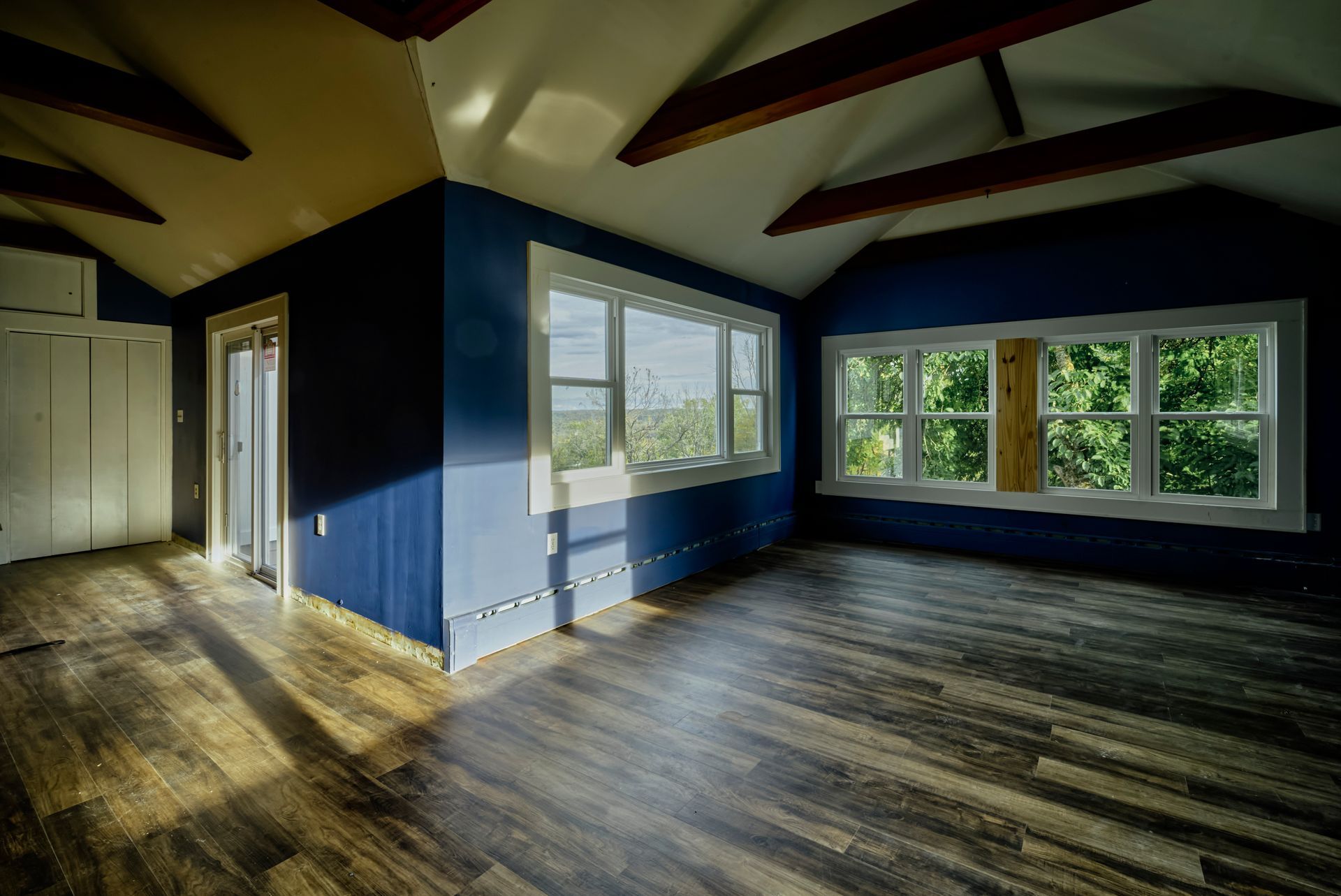 An empty room with a lot of windows and a wooden floor.