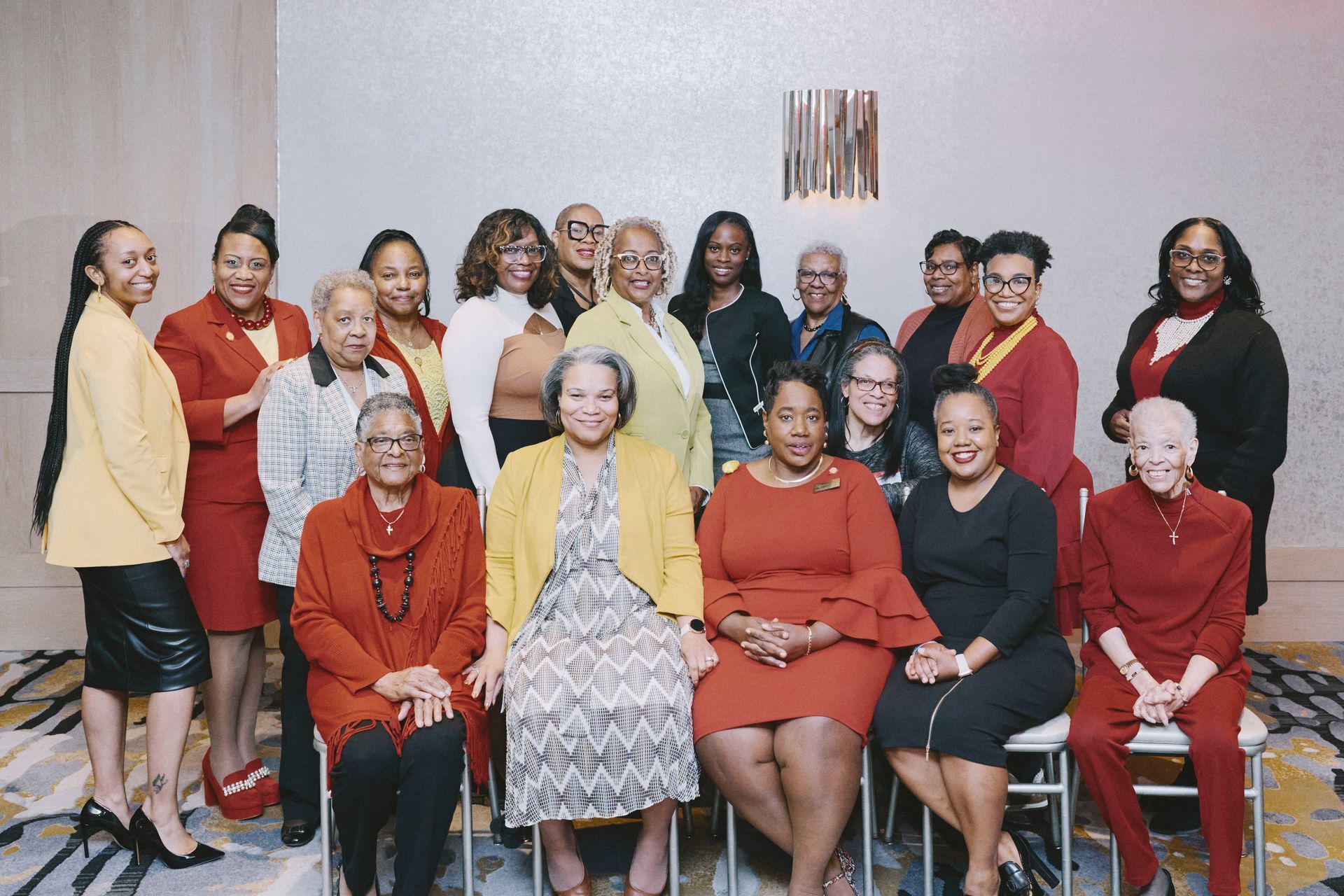 Group of women pose for photo in a hotel, many in red and yellow.