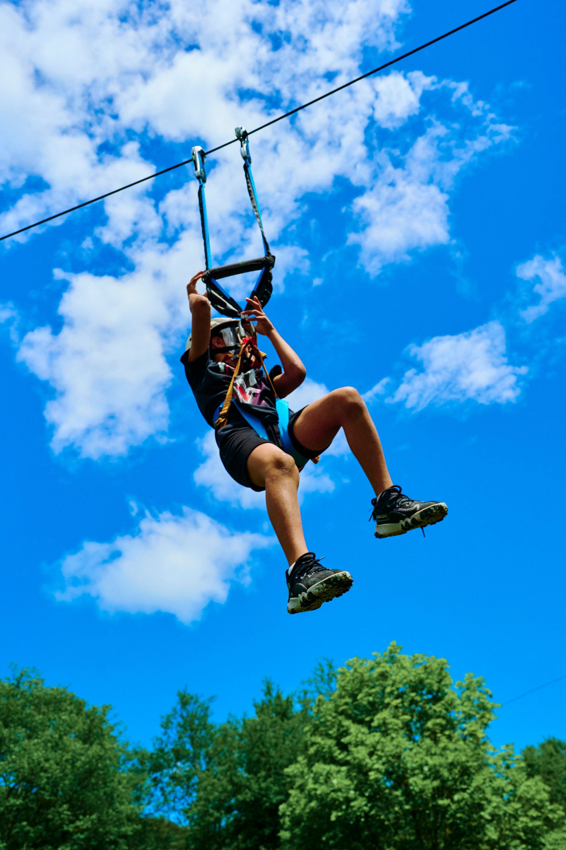 A person is flying through the air on a zip line.