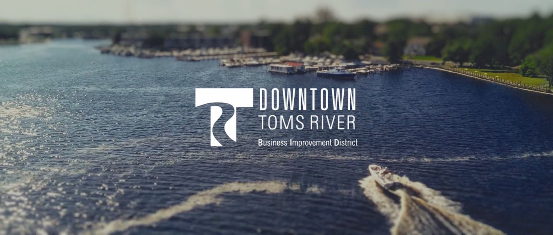 A red convertible parked on a street in front of a white building with other cars.