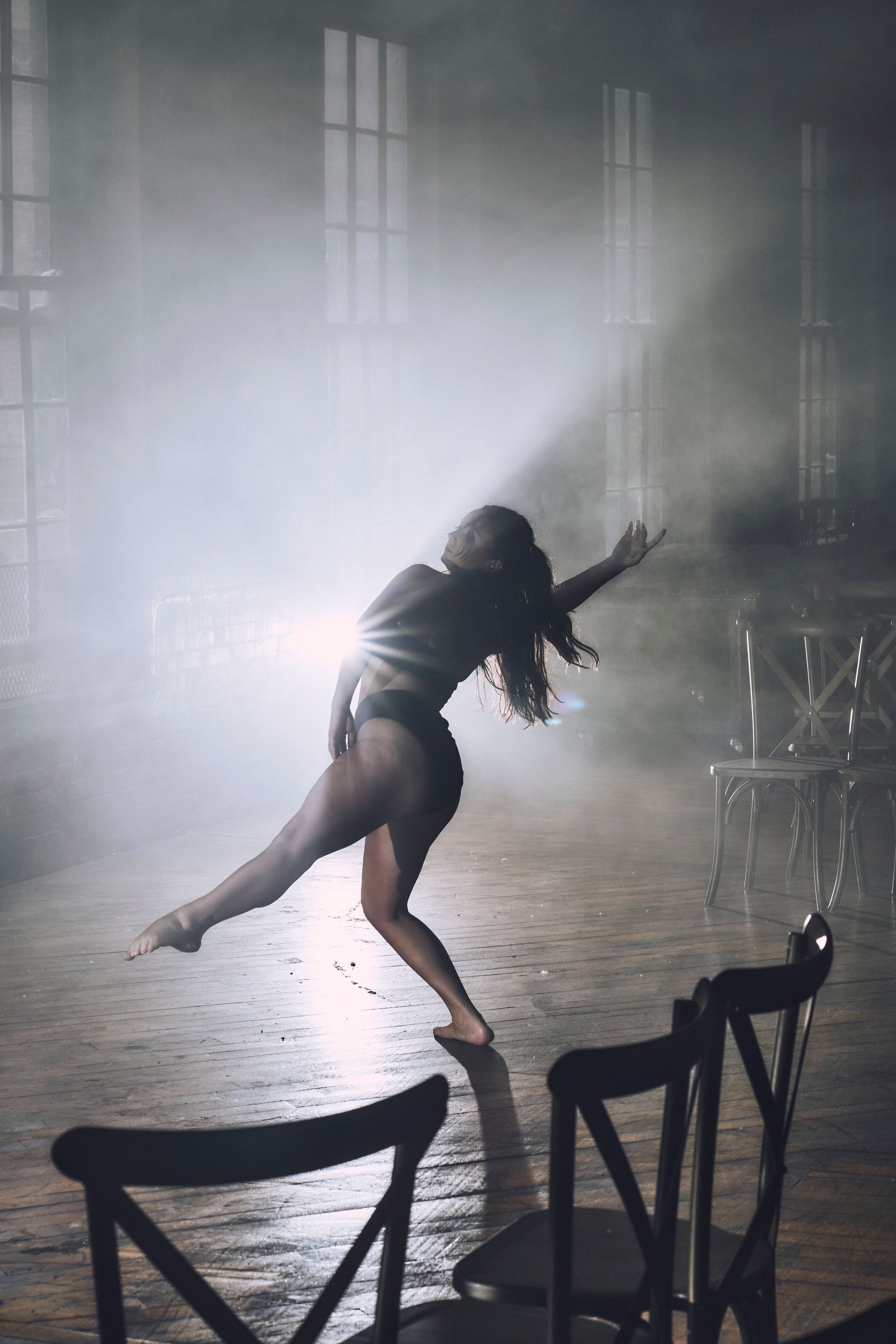 Four dancers in mid-air splits, outdoors near industrial structures.