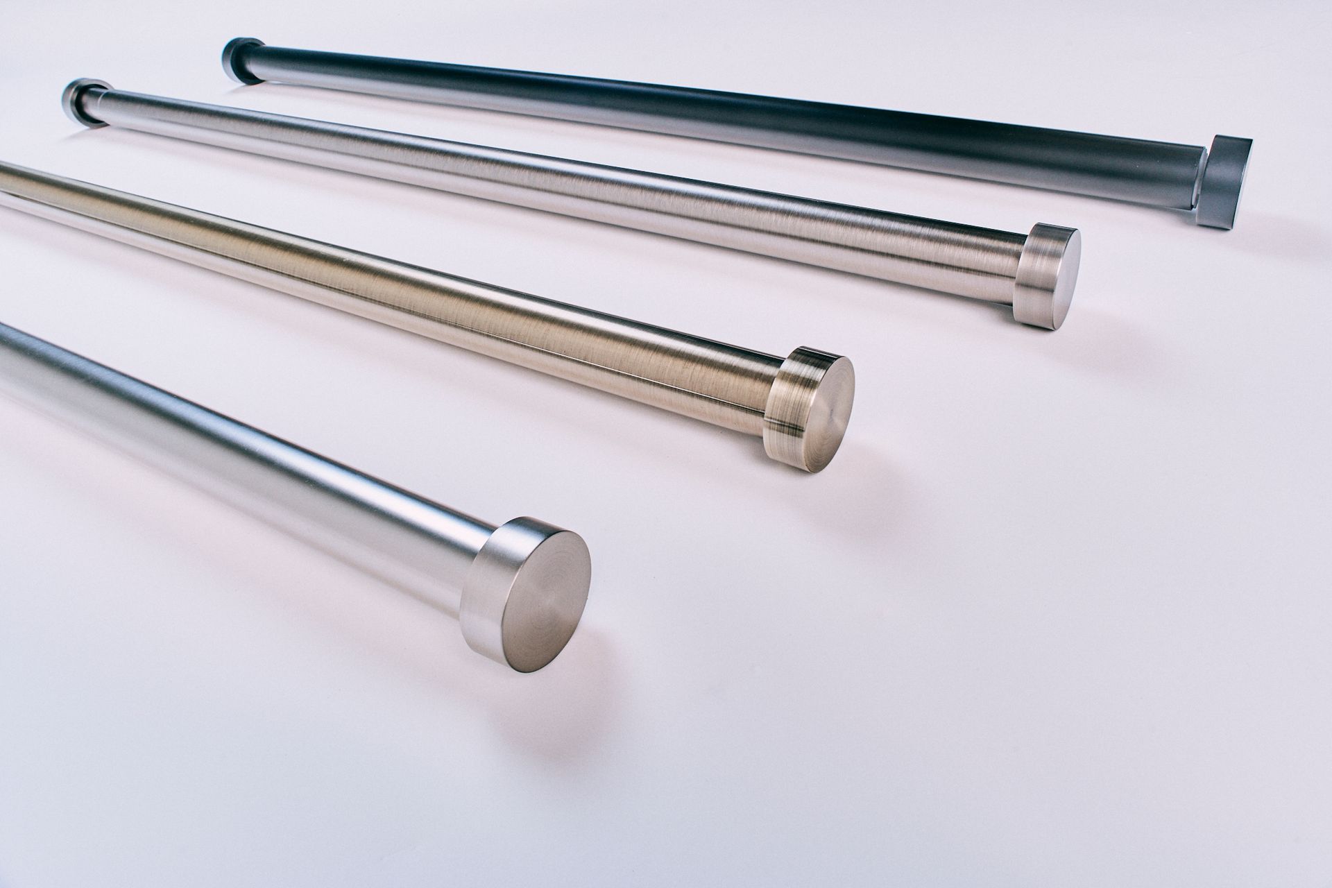 Four stainless steel rods are lined up on a white surface