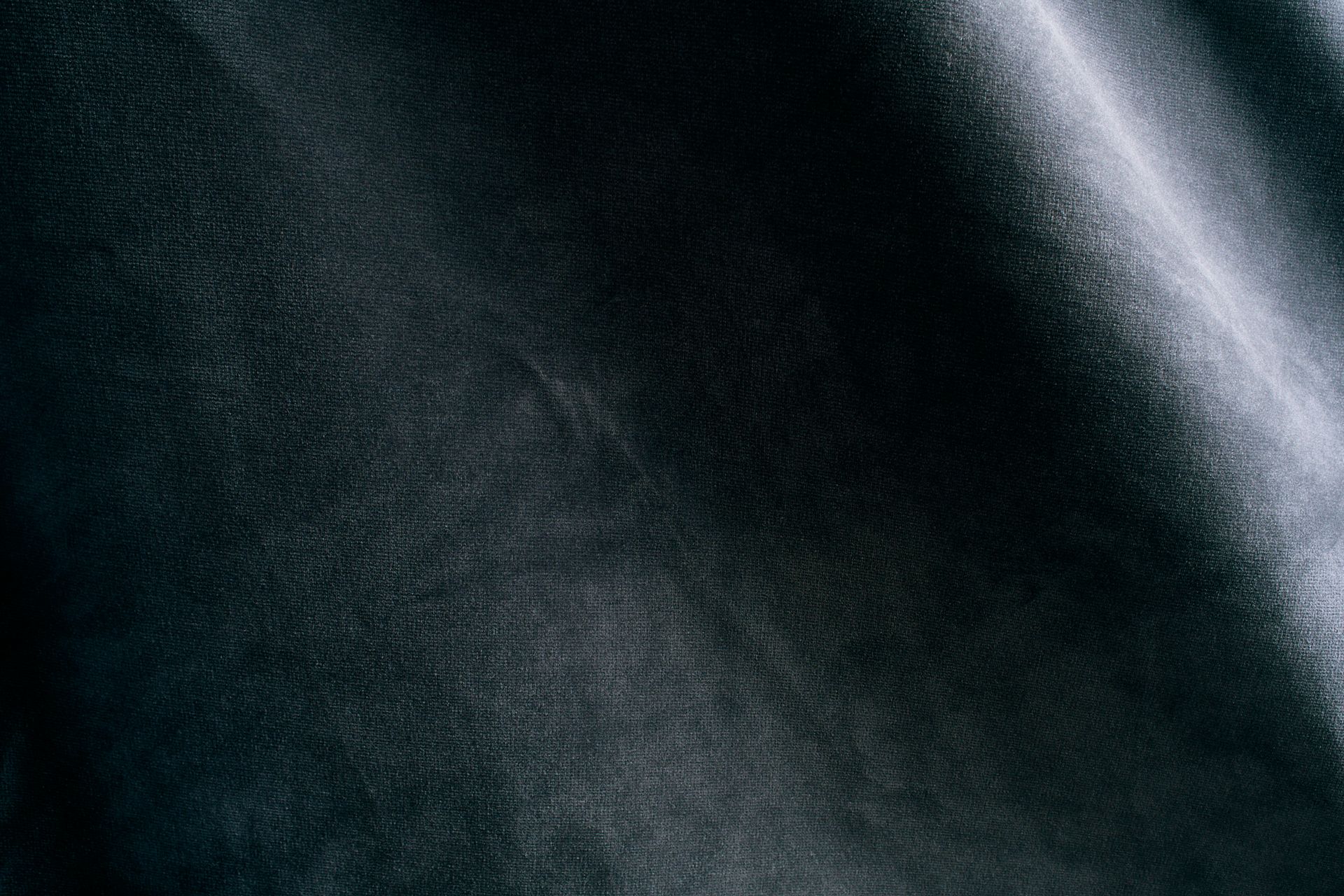 A close up of a black fabric texture with a slight wave.