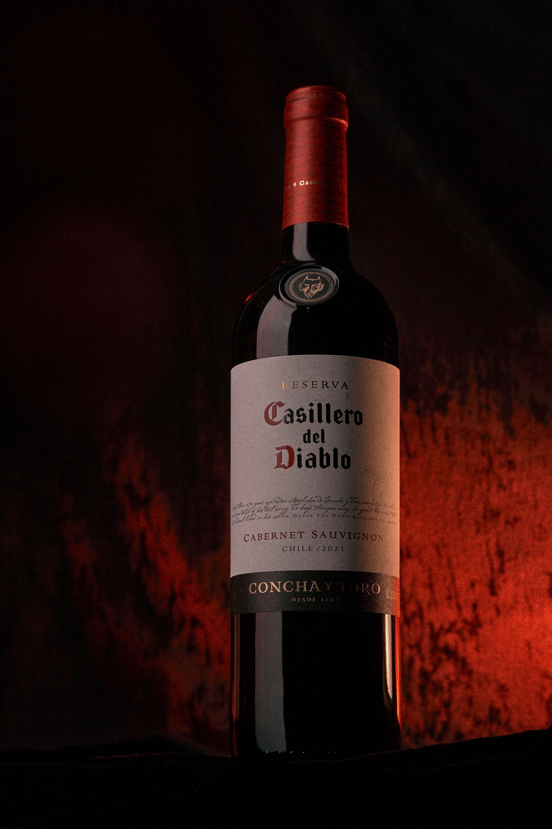 Bottle of Casillero del Diablo red wine, against a dark, red-lit backdrop.